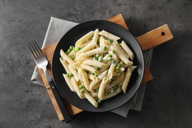 Photo of Delicious pasta with green peas, cheese and fork on grey table, top view