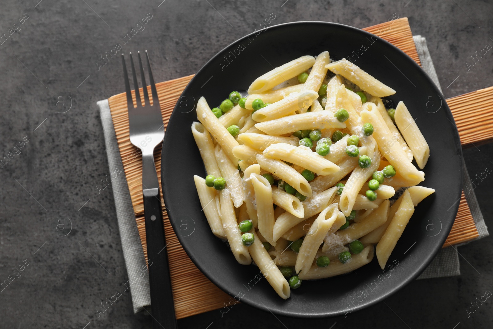 Photo of Delicious pasta with green peas, cheese and fork on grey table, top view