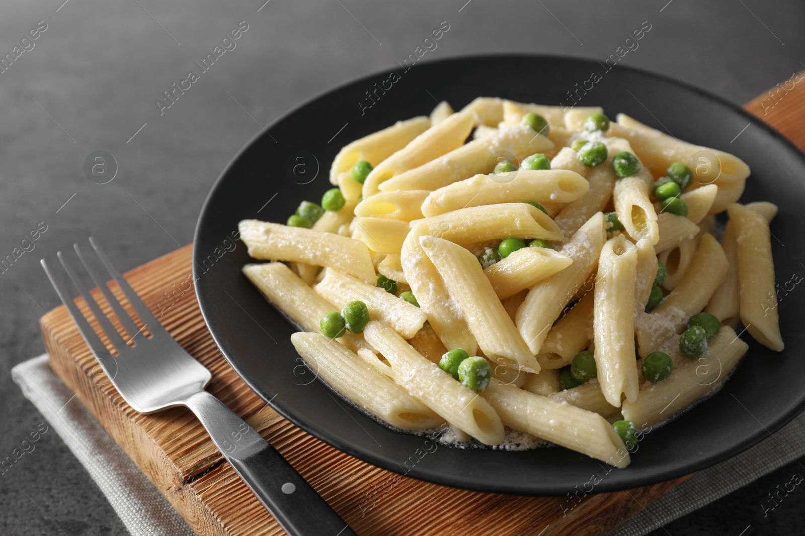 Photo of Delicious pasta with green peas, cheese and fork on grey table