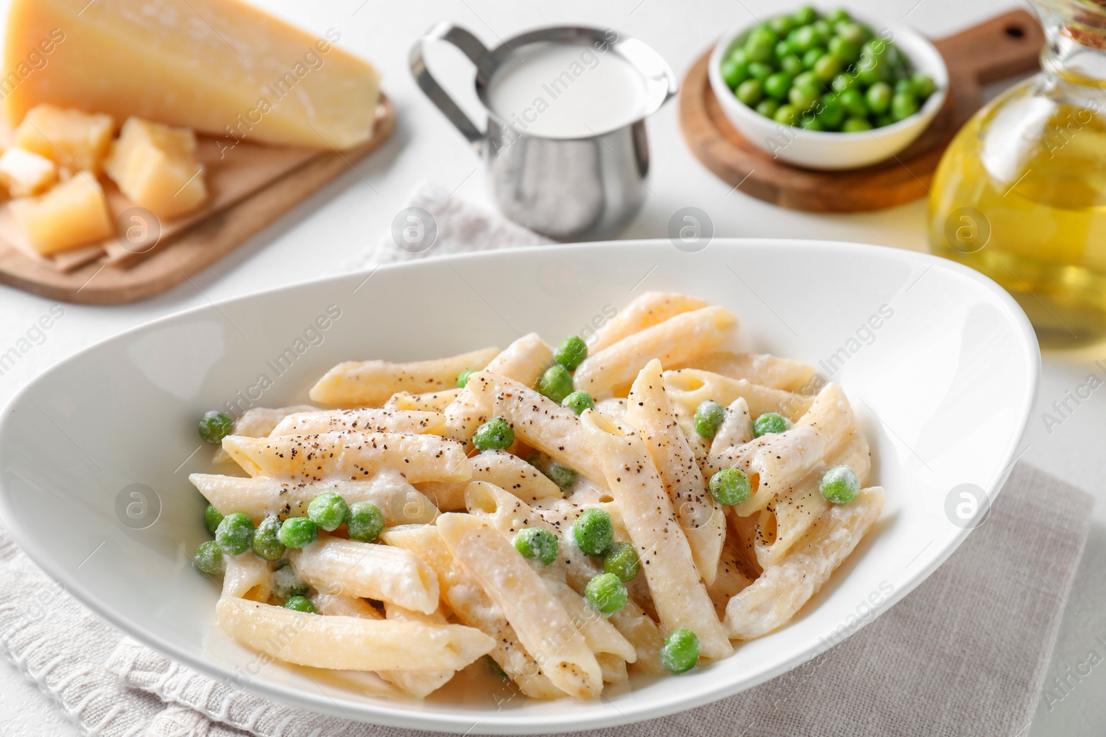 Photo of Delicious pasta with green peas and other ingredients on white table