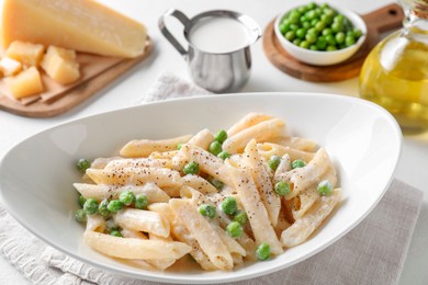 Delicious pasta with green peas and other ingredients on white table