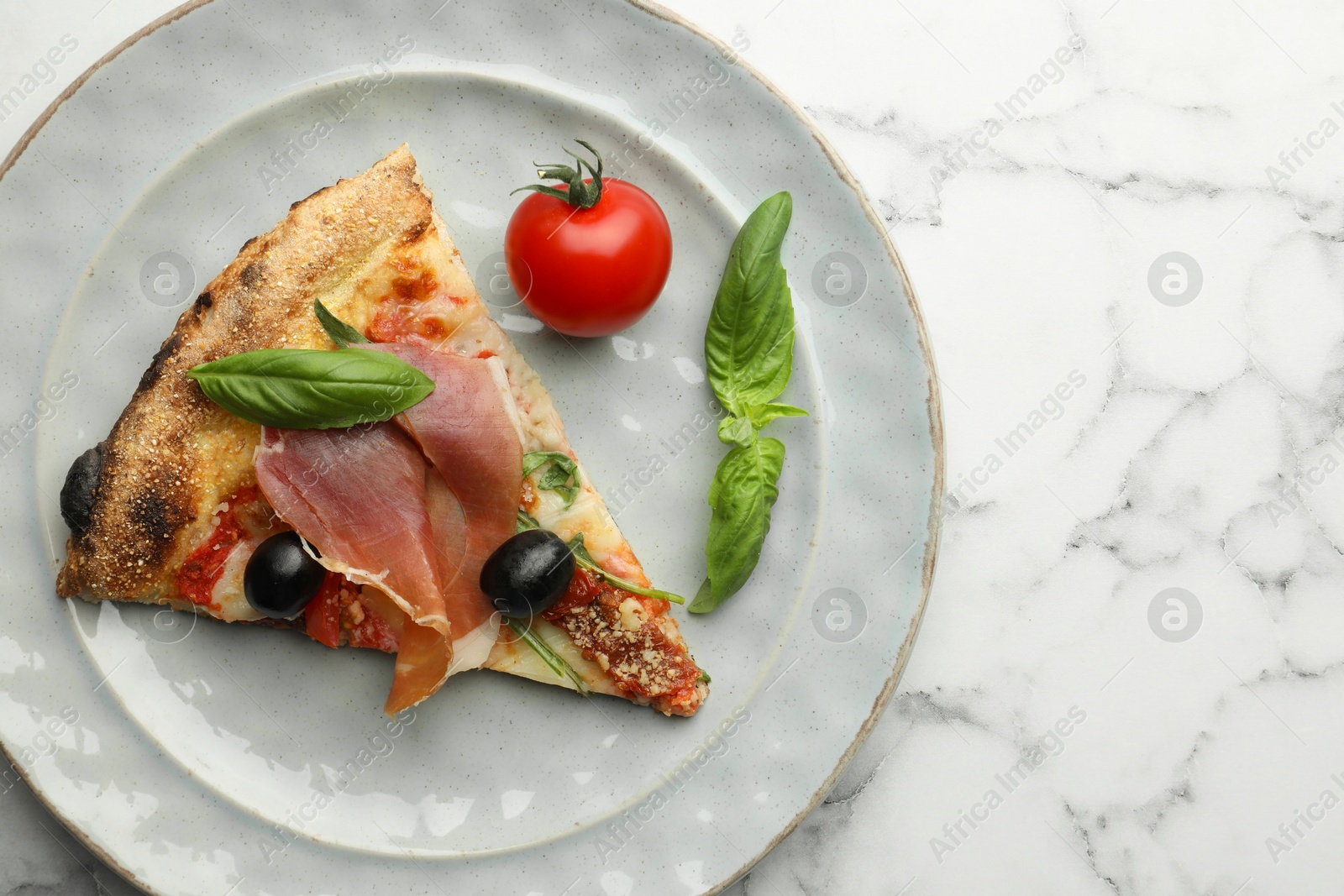 Photo of Tasty pizza with cured ham, olives, tomato and basil on white marble table, top view. Space for text