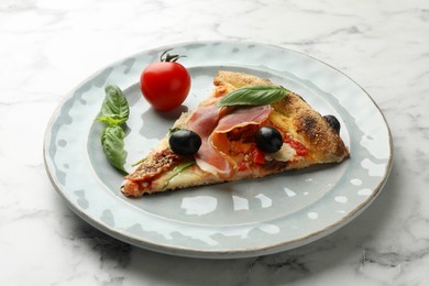 Tasty pizza with cured ham, olives, tomato and basil on white marble table