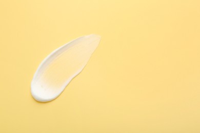 Sample of face cream on yellow background, top view. Space for text