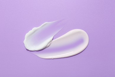 Photo of Samples of face cream on violet background, top view