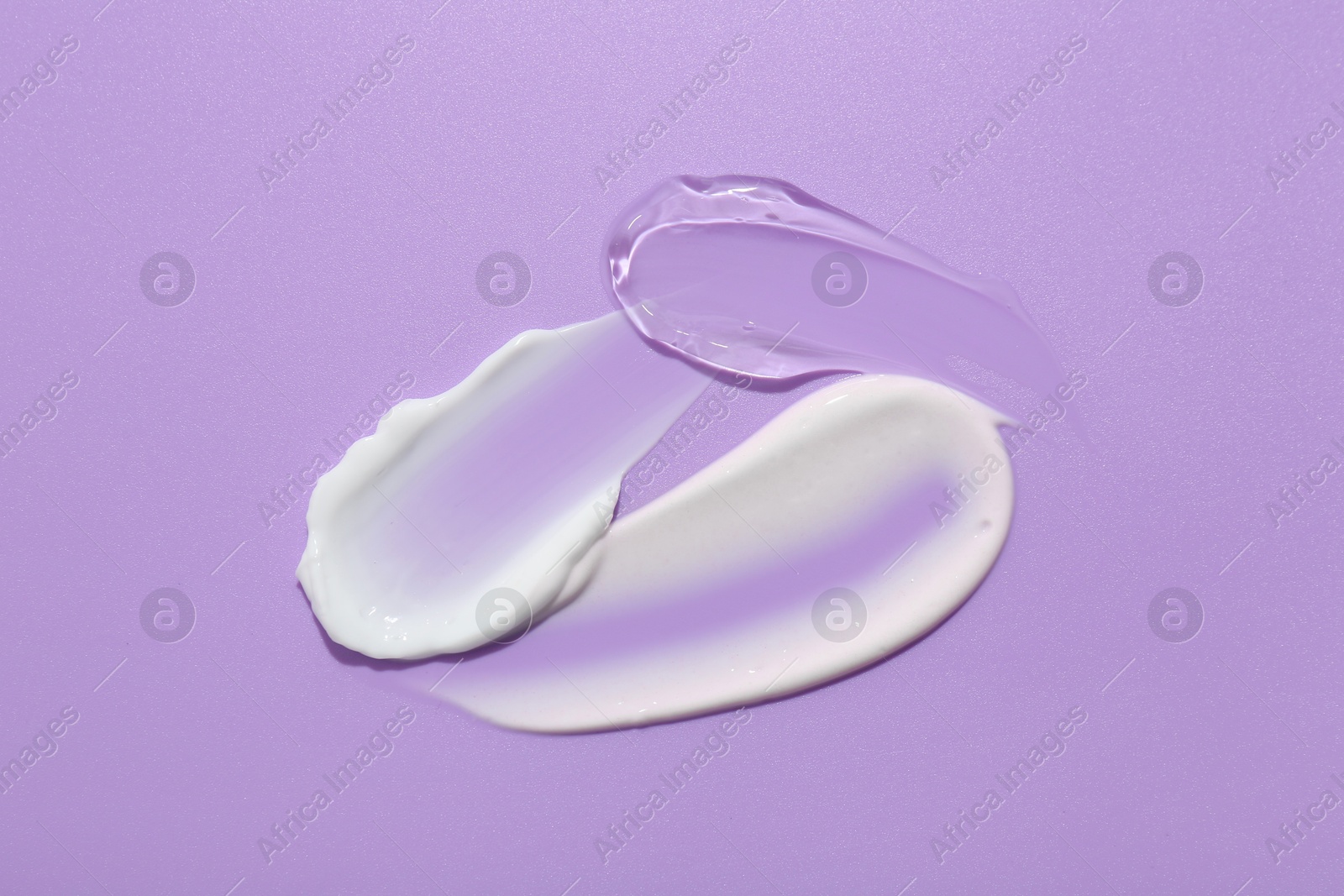 Photo of Samples of face cream on violet background, top view