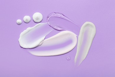 Photo of Samples of face cream on violet background, top view