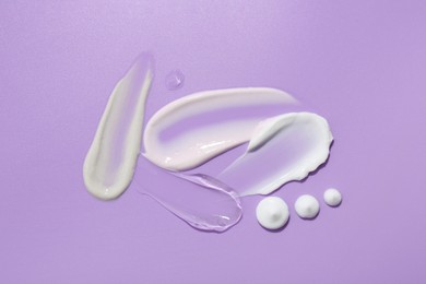 Photo of Samples of face cream on violet background, top view