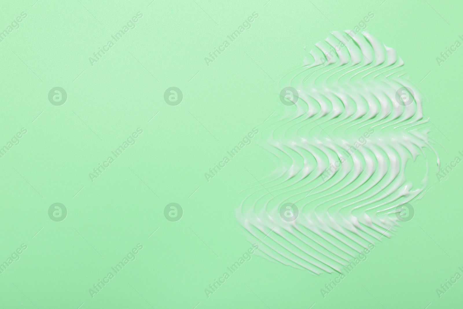 Photo of Face cream on green background, top view. Space for text