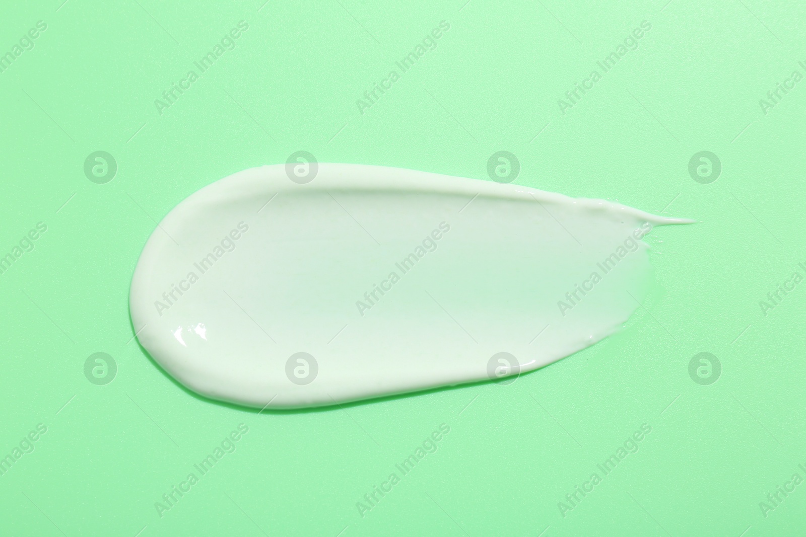 Photo of Sample of face cream on green background, top view