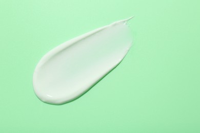 Photo of Sample of face cream on green background, top view. Space for text