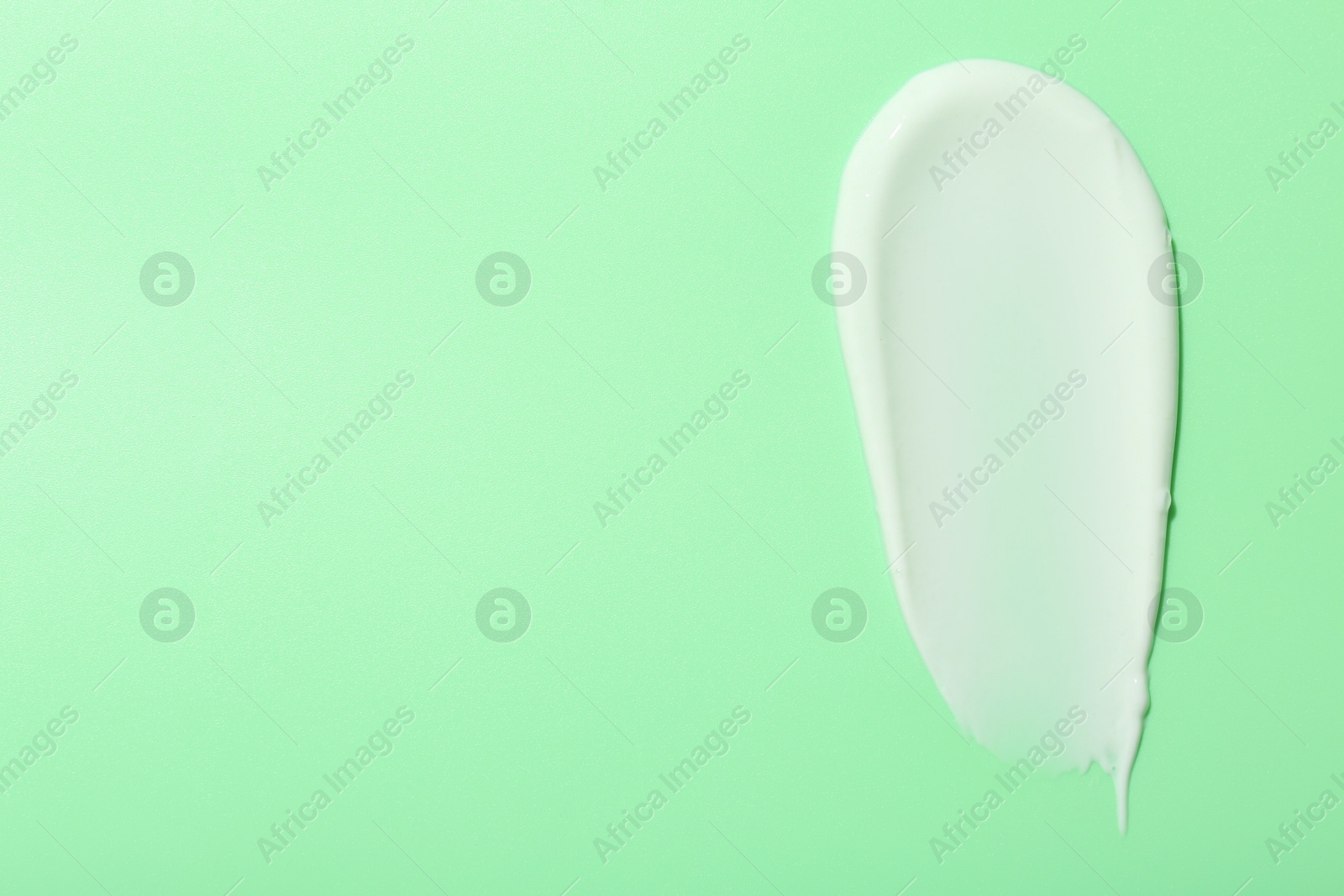 Photo of Sample of face cream on green background, top view. Space for text