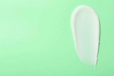 Photo of Sample of face cream on green background, top view. Space for text