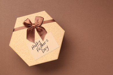 Photo of Card with phrase Happy Father's Day and gift box on light brown background, top view. Space for text