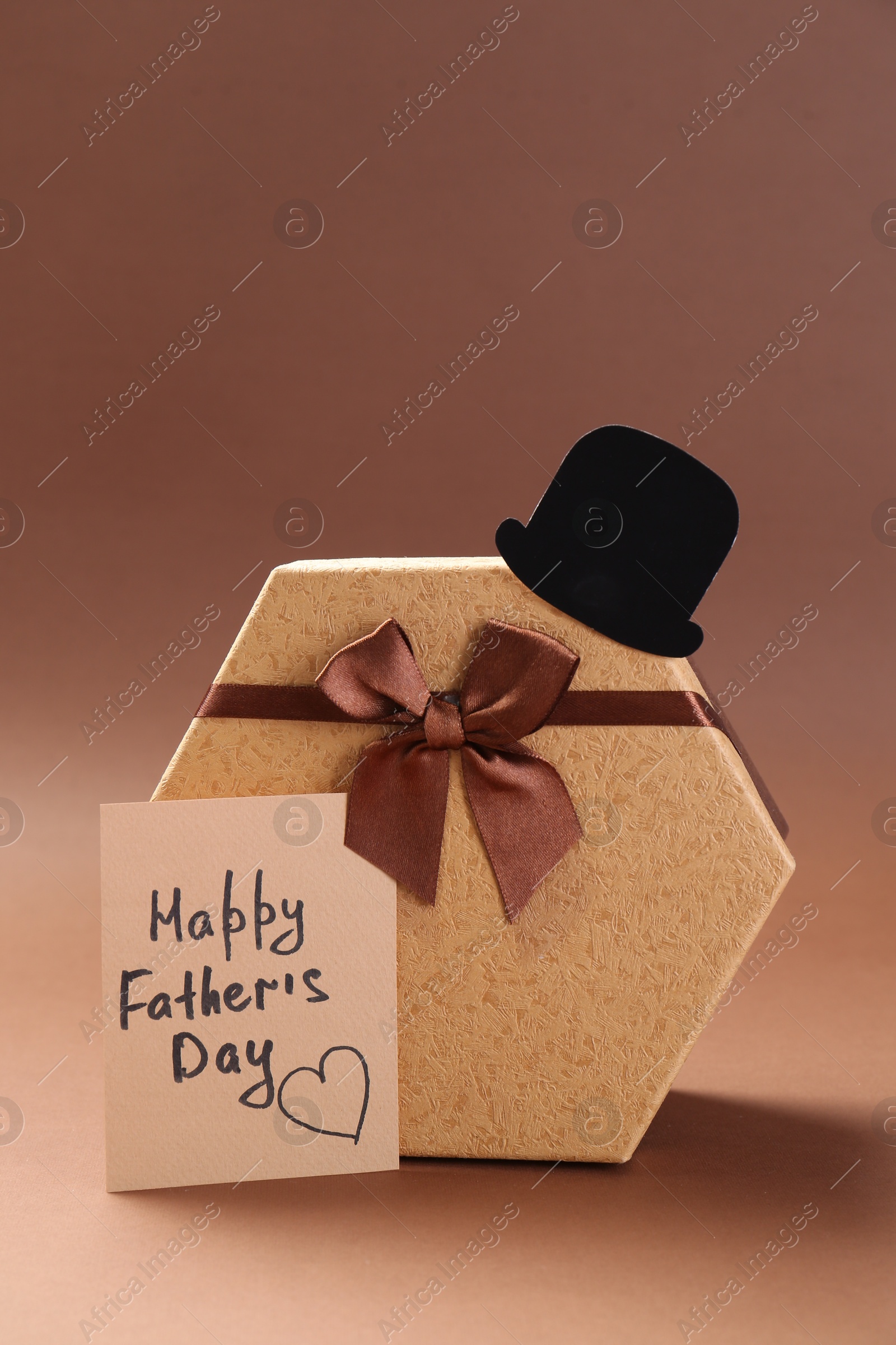 Photo of Card with phrase Happy Father's Day, hat and gift box on light brown background