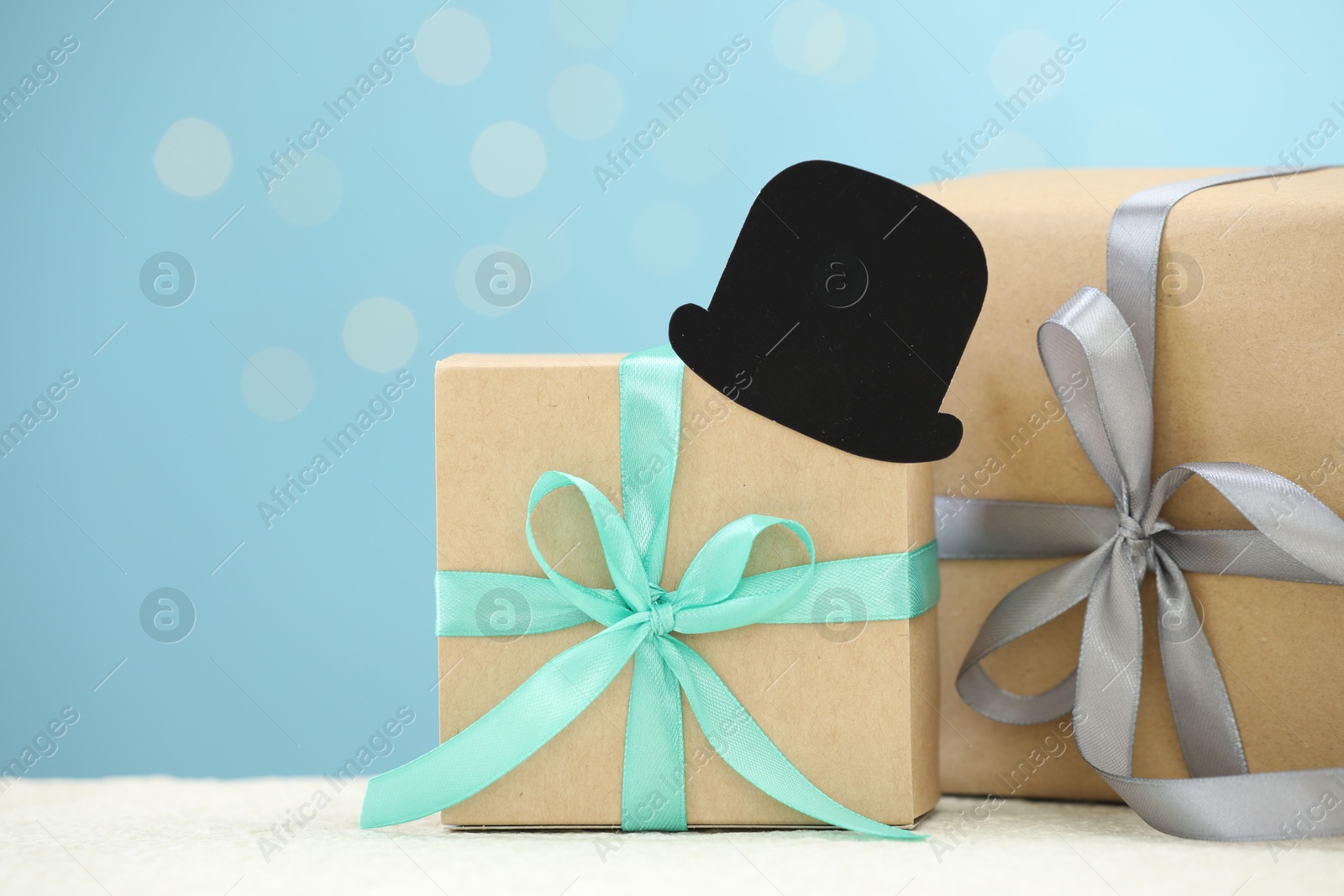 Photo of Happy Father's Day, gift boxes and paper hat on light table, space for text