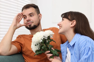 Photo of Obsessive woman with flowers flirting with embarrassed man at home