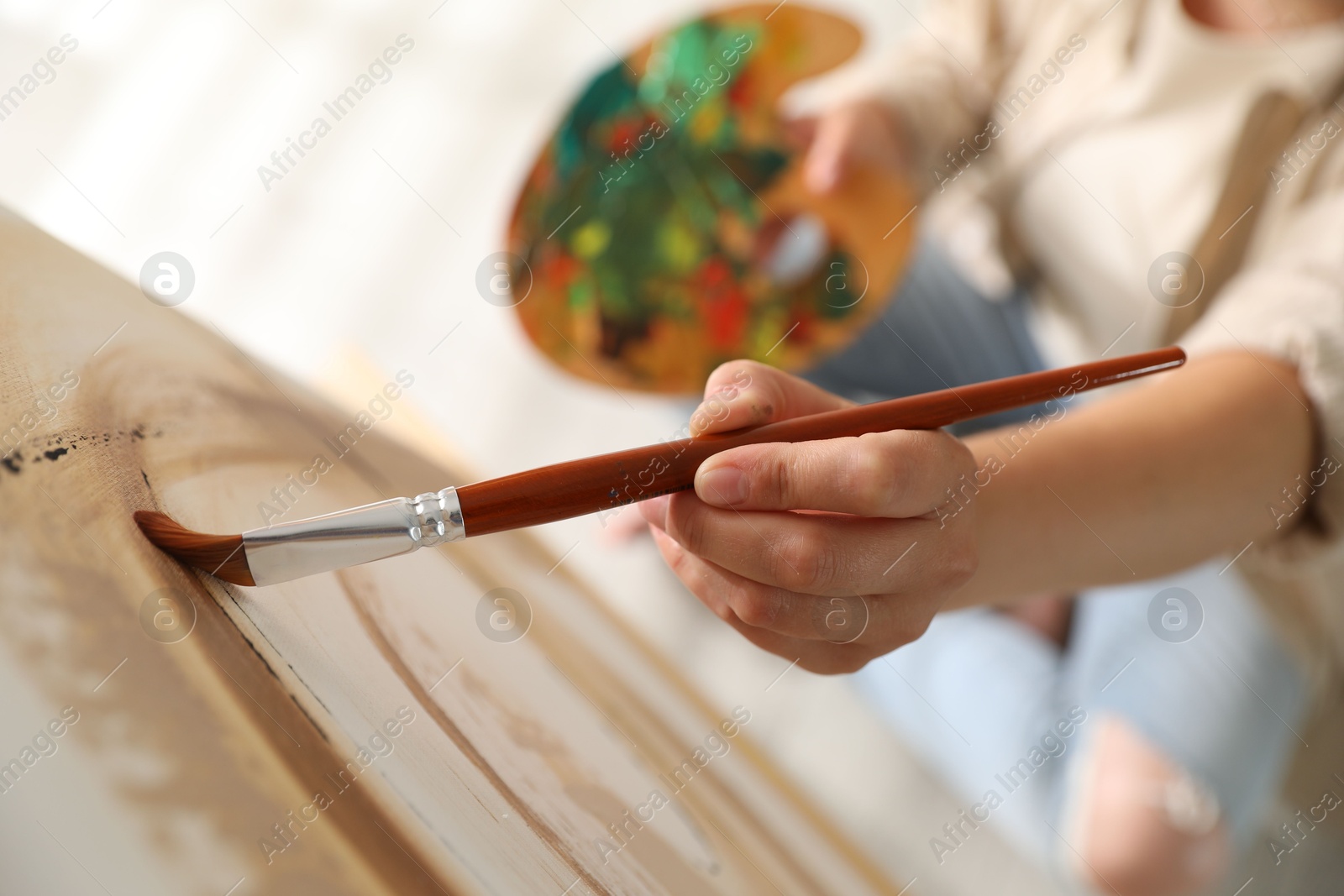 Photo of Woman painting on easel with canvas indoors, closeup