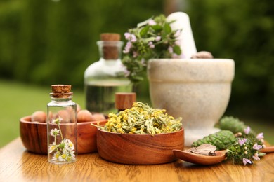 Different ingredients for tincture, bottles, mortar and pestle on wooden table outdoors