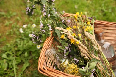 Photo of Tincture and flowers in wicker basket outdoors, closeup. Space for text