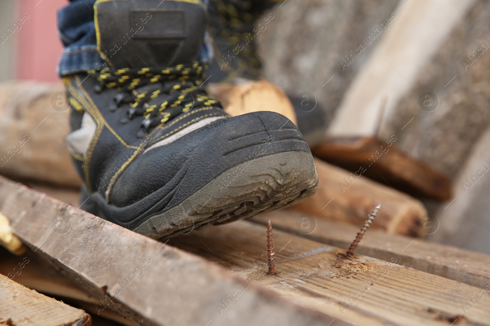 Photo of Careless worker stepping on nail in wooden plank outdoors, closeup