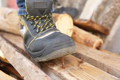 Photo of Careless worker stepping on nail in wooden plank outdoors, closeup