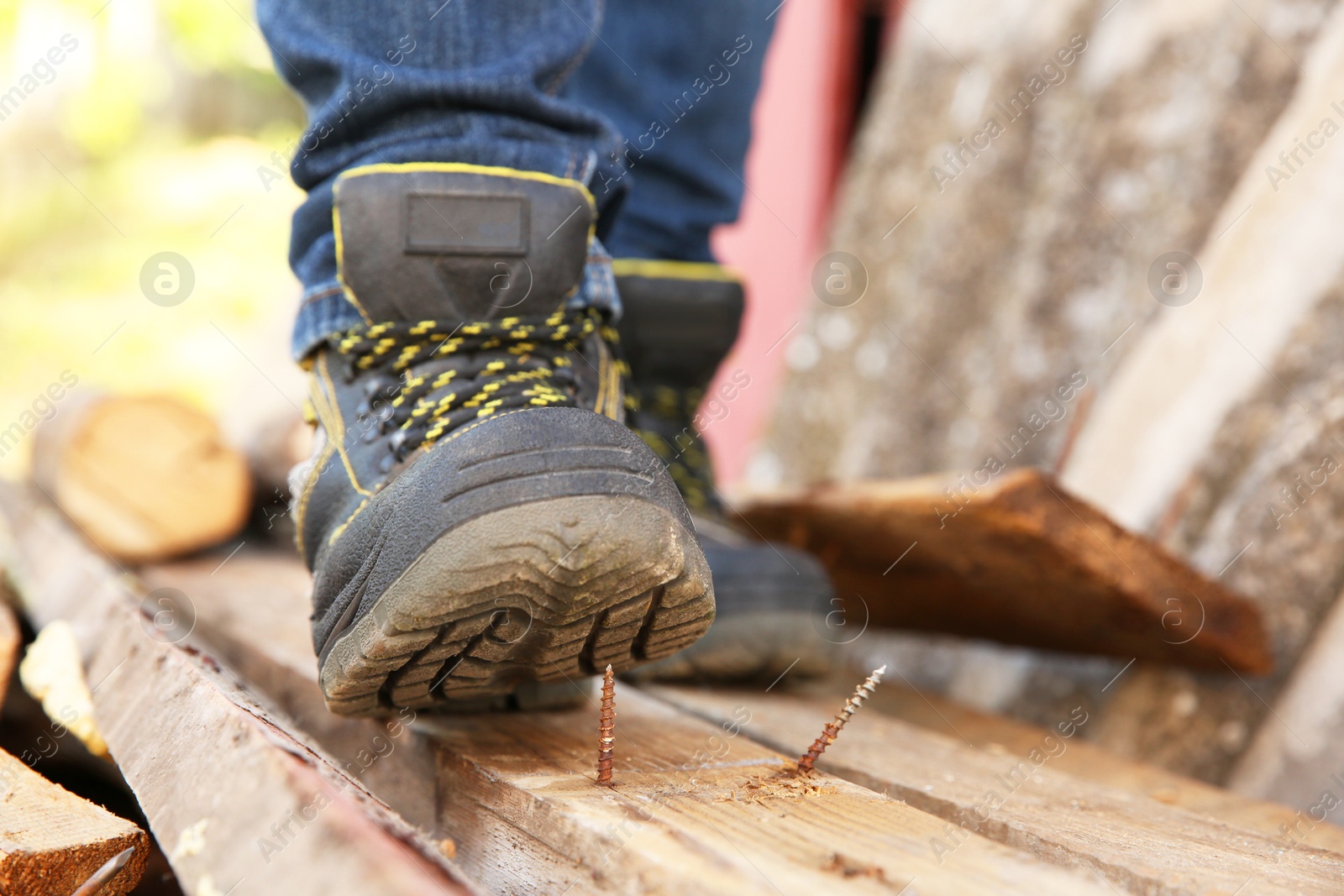 Photo of Careless worker stepping on nail in wooden plank outdoors, closeup