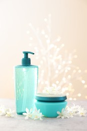 Photo of Cosmetic products and beautiful jasmine flowers on grey table