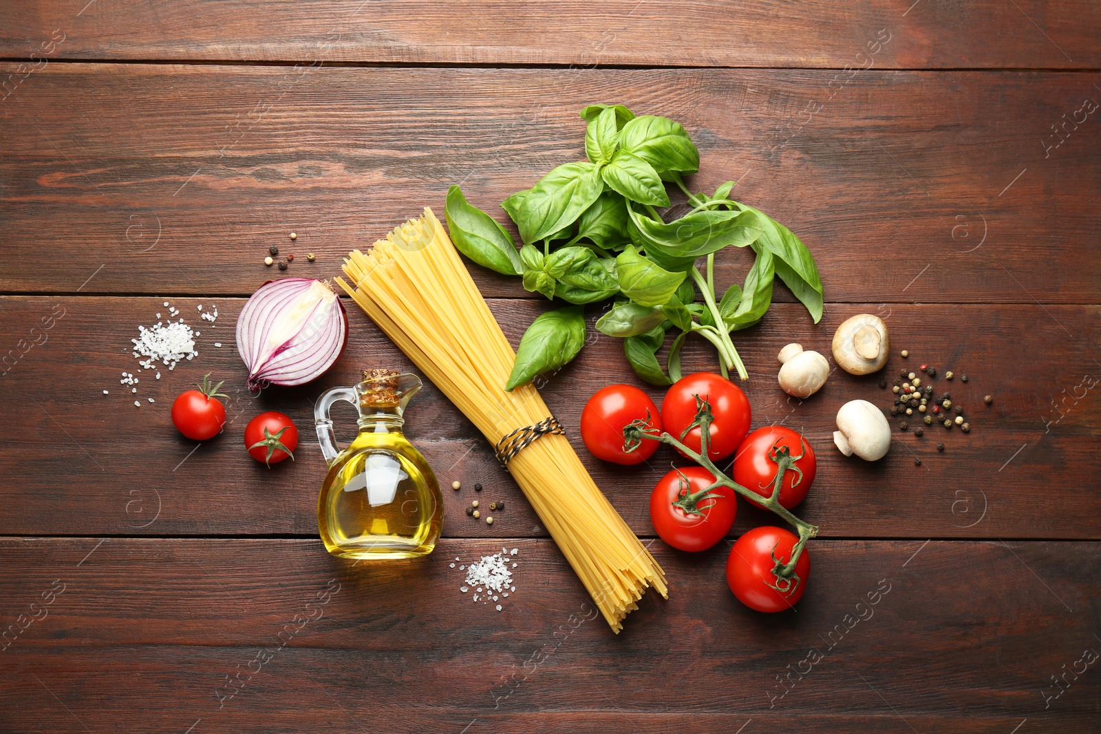 Photo of Raw pasta, spices and products on wooden table, flat lay