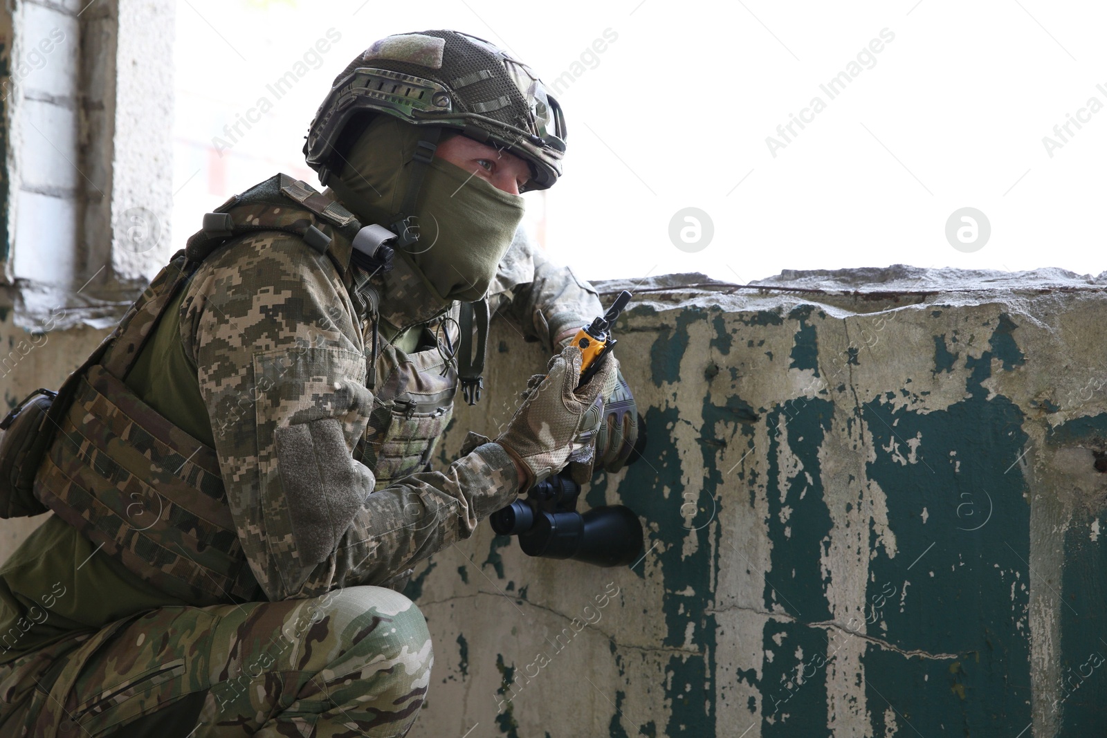 Photo of Military mission. Soldier in uniform with radio transmitter inside abandoned building, space for text