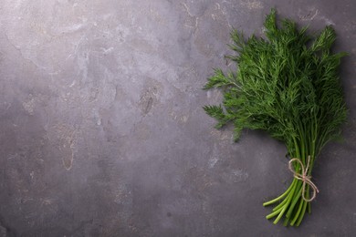 Photo of Bunch of fresh dill on grey textured table, top view. Space for text