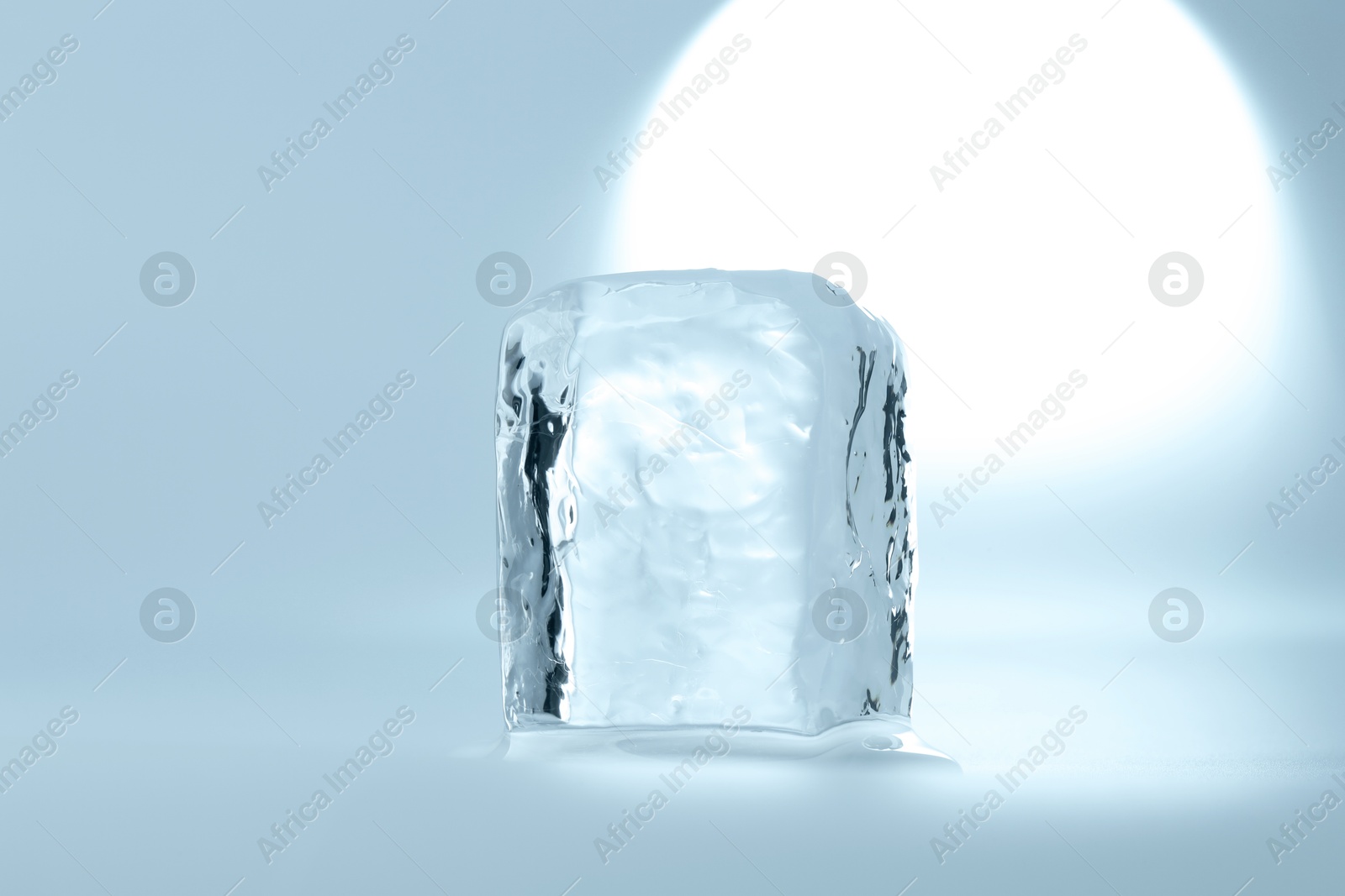 Photo of Cube of clear ice on light blue background