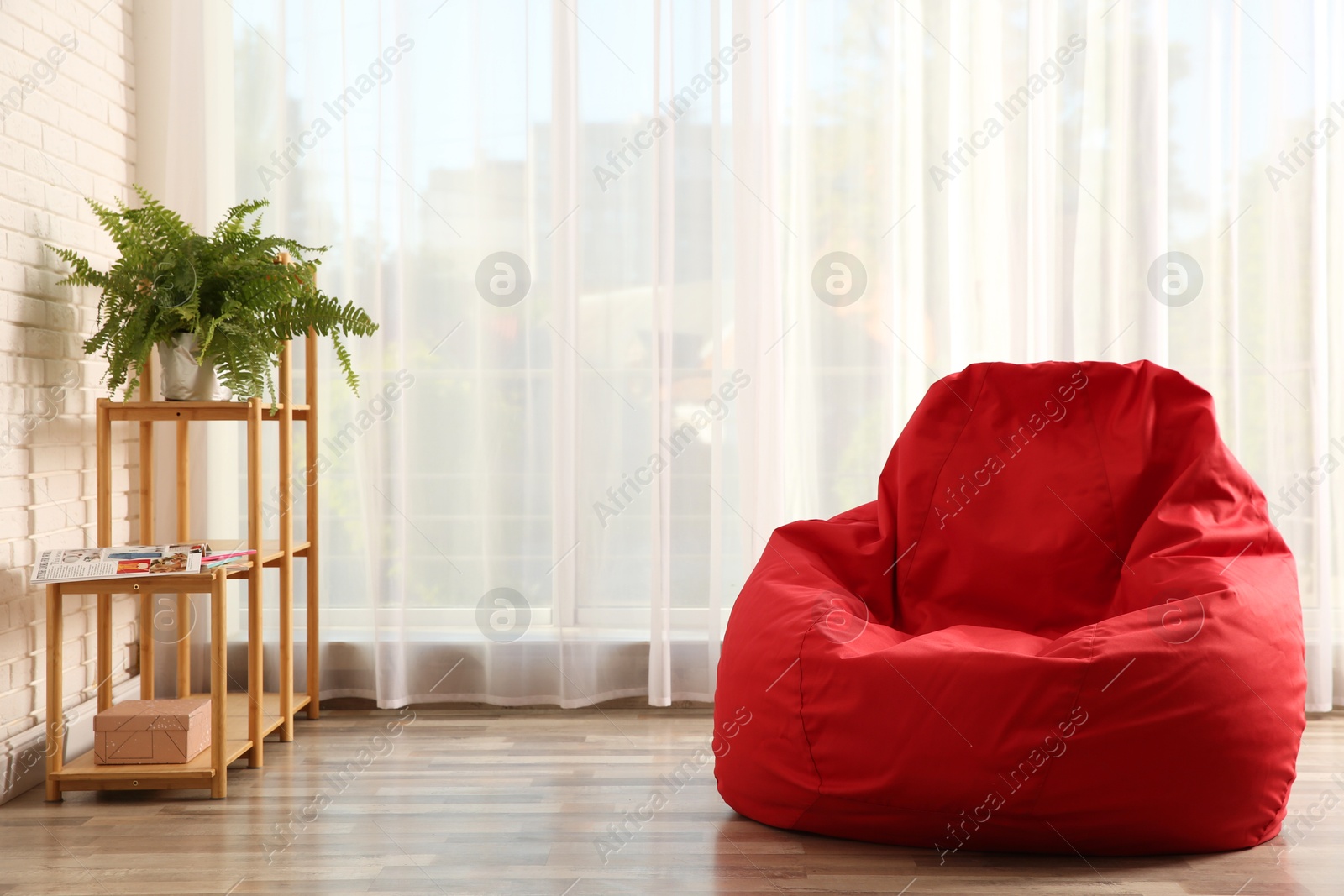 Photo of Red bean bag chair on floor in room. Space for text