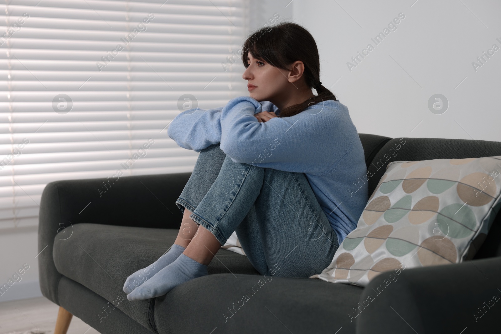 Photo of Loneliness concept. Sad woman sitting on sofa at home