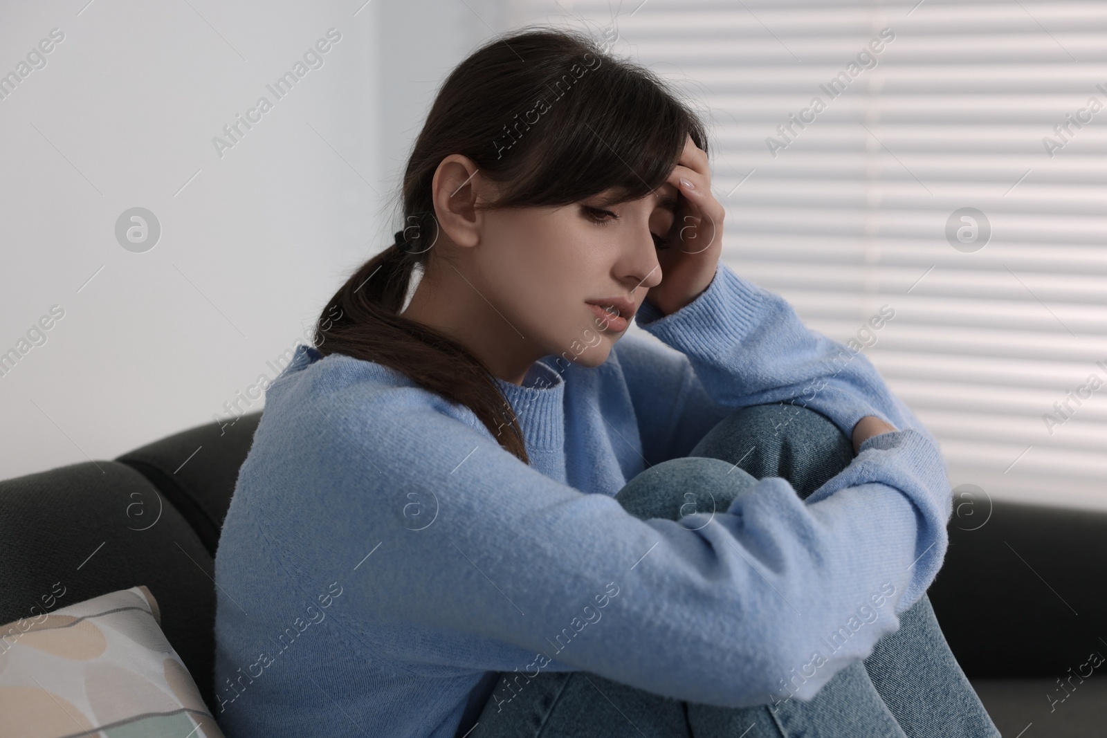 Photo of Loneliness concept. Sad woman sitting on sofa at home