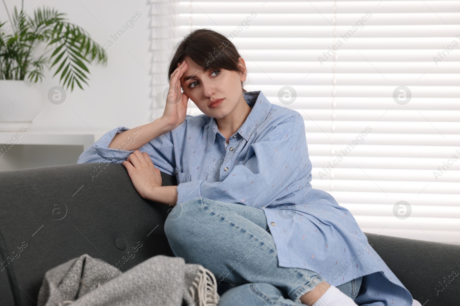 Photo of Loneliness concept. Sad woman sitting on sofa at home