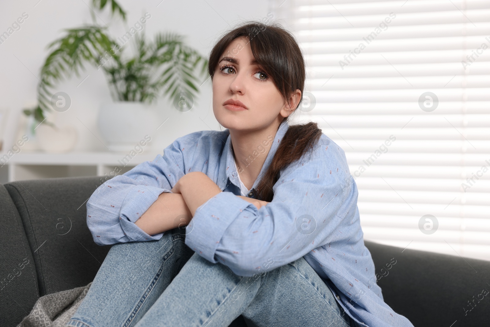 Photo of Loneliness concept. Sad woman sitting on sofa at home