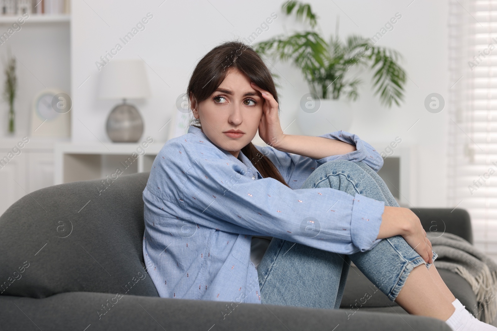 Photo of Loneliness concept. Sad woman sitting on sofa at home