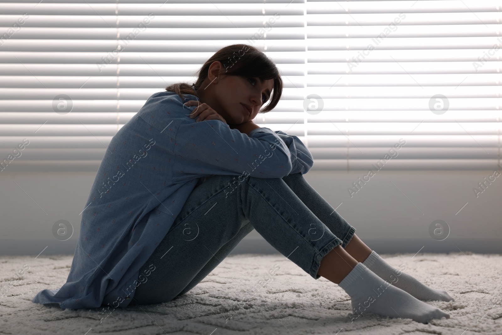 Photo of Loneliness concept. Sad woman sitting on floor at home