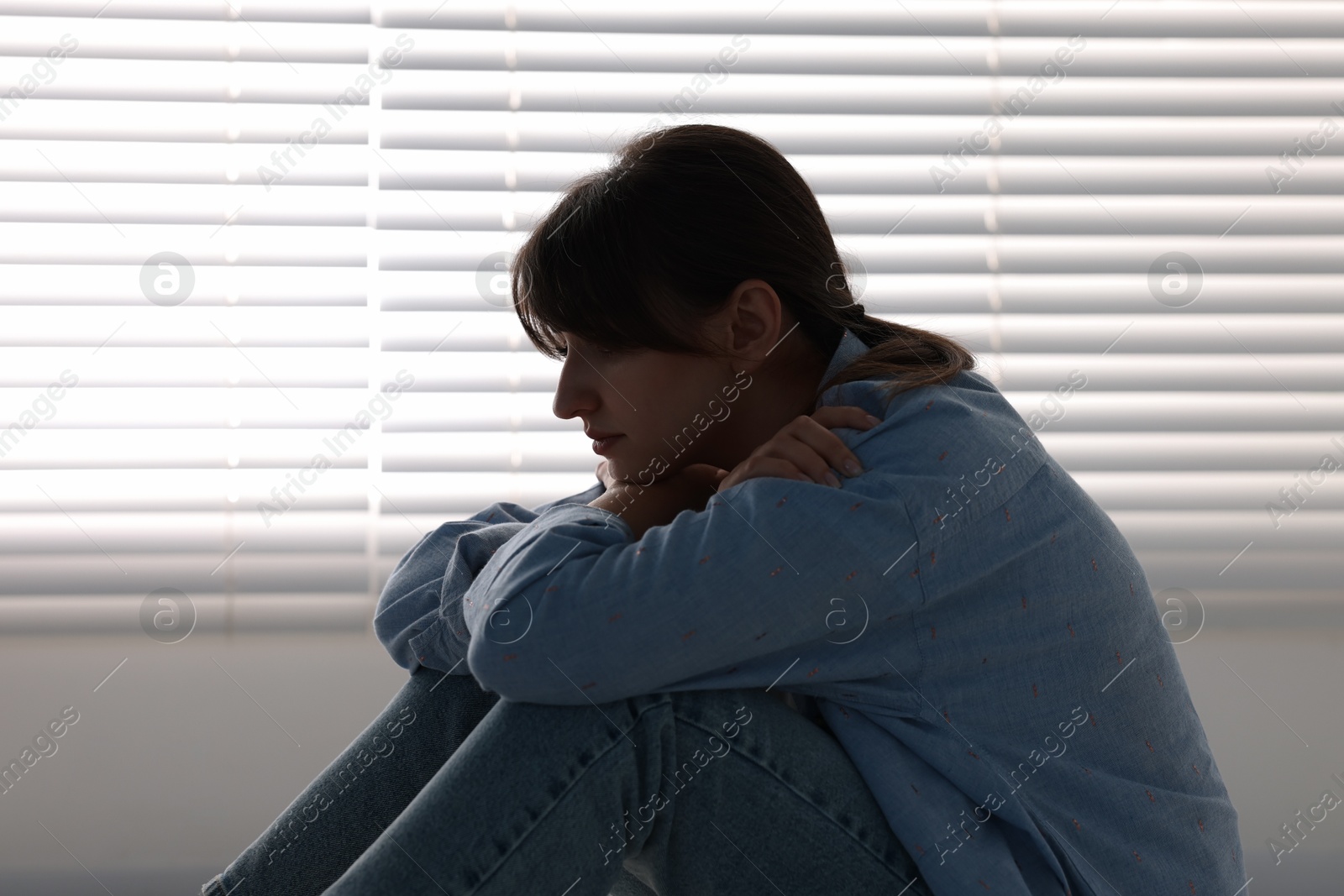 Photo of Loneliness concept. Sad woman sitting on floor at home