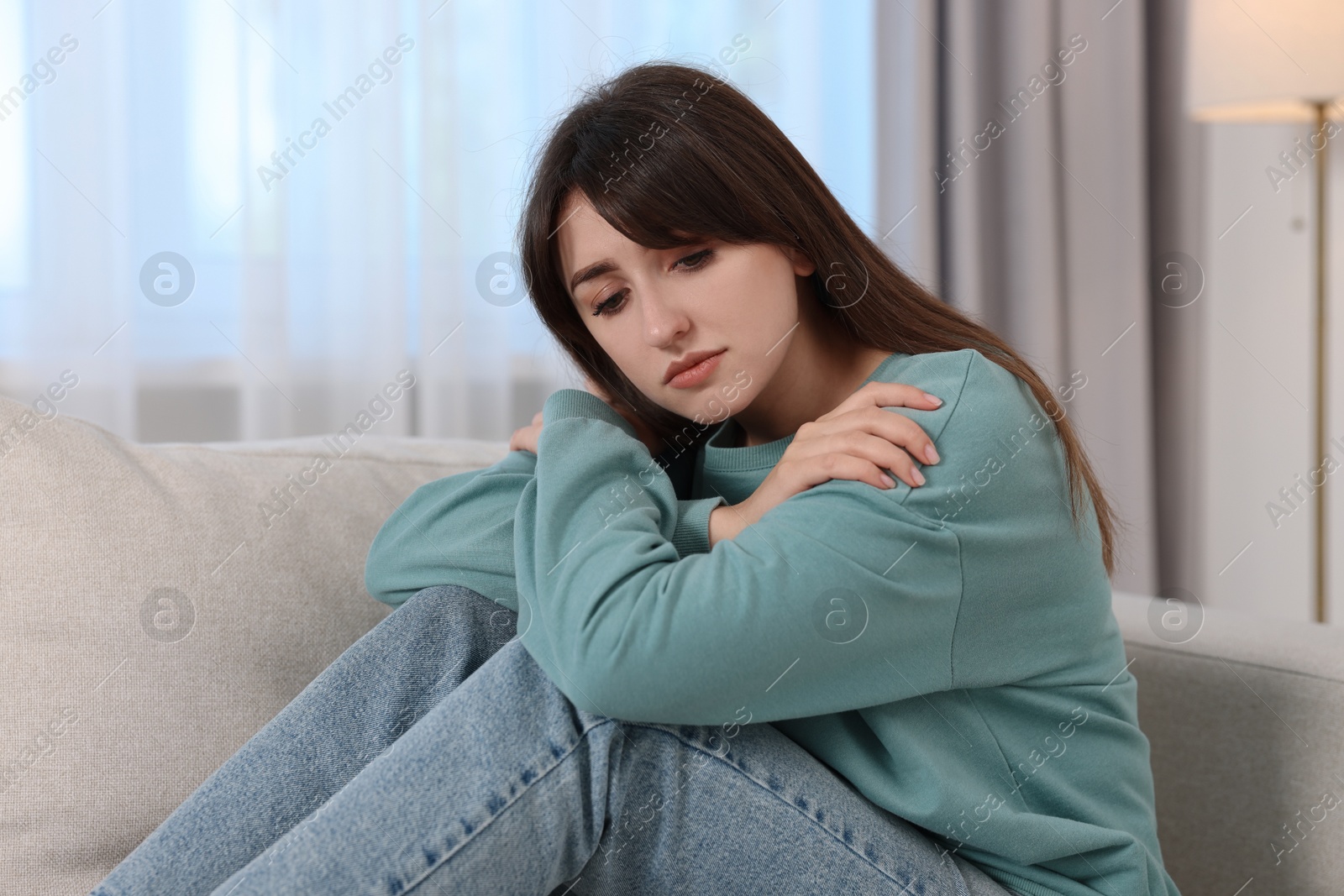 Photo of Loneliness concept. Sad woman sitting on sofa at home