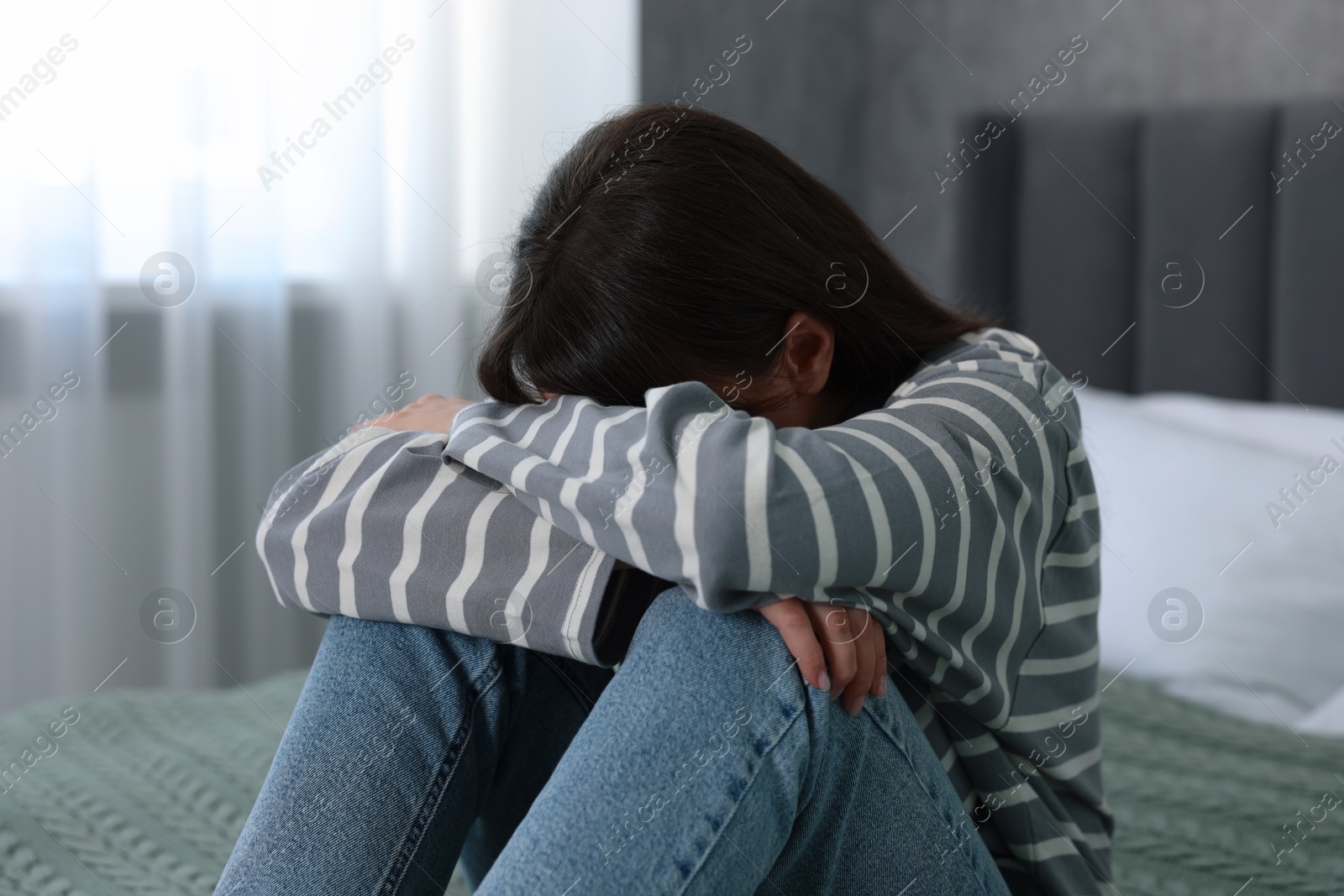 Photo of Loneliness concept. Sad woman sitting on bed at home