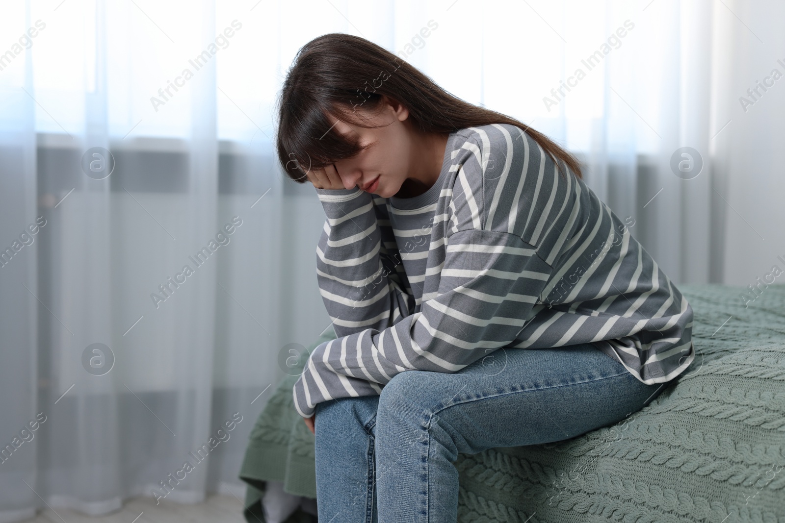 Photo of Loneliness concept. Sad woman sitting on bed at home