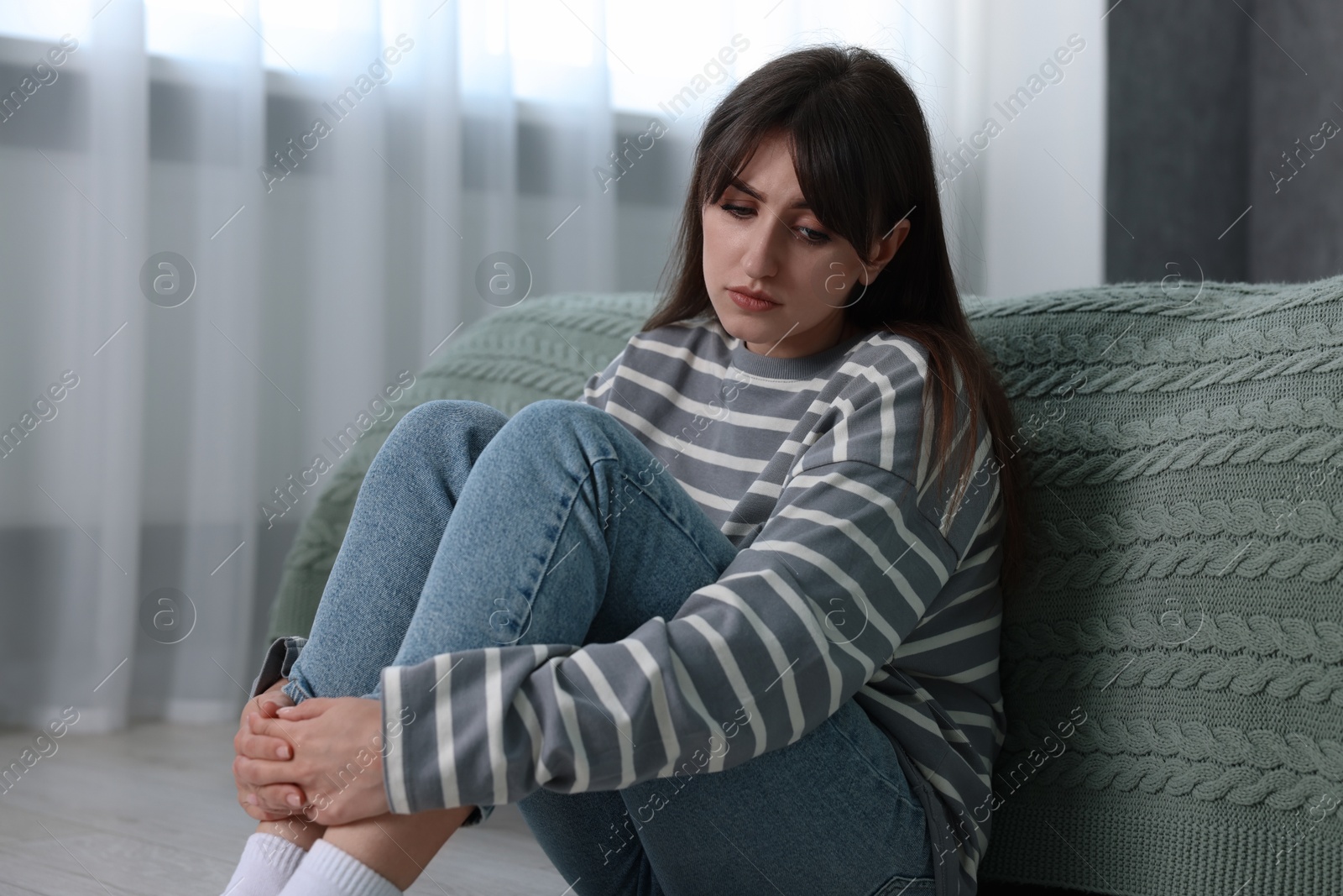 Photo of Loneliness concept. Sad woman sitting on floor at home