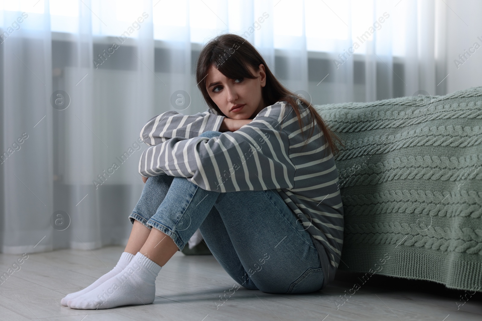 Photo of Loneliness concept. Sad woman sitting on floor at home