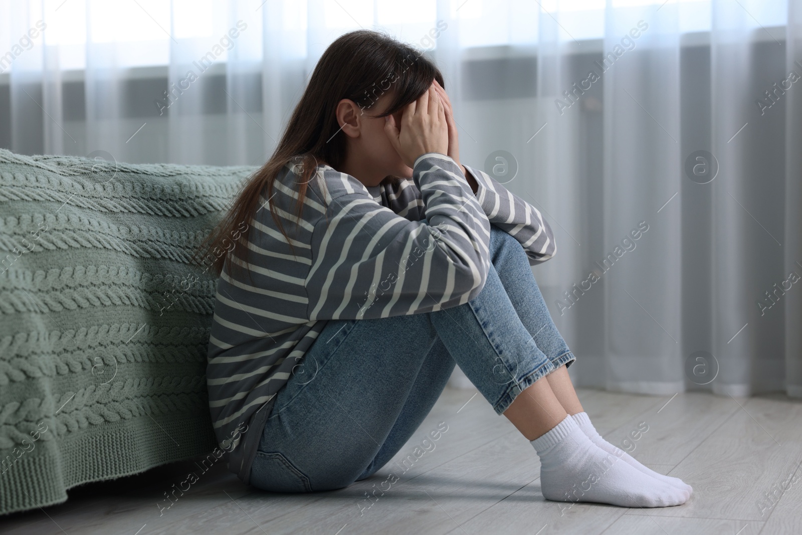 Photo of Loneliness concept. Sad woman sitting on floor at home