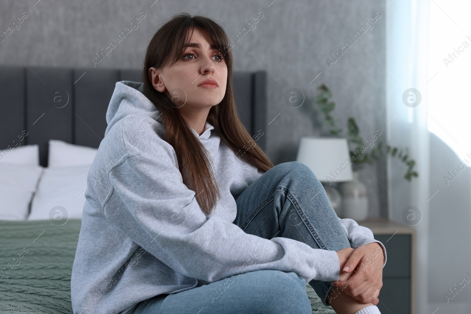 Photo of Loneliness concept. Sad woman sitting on bed at home