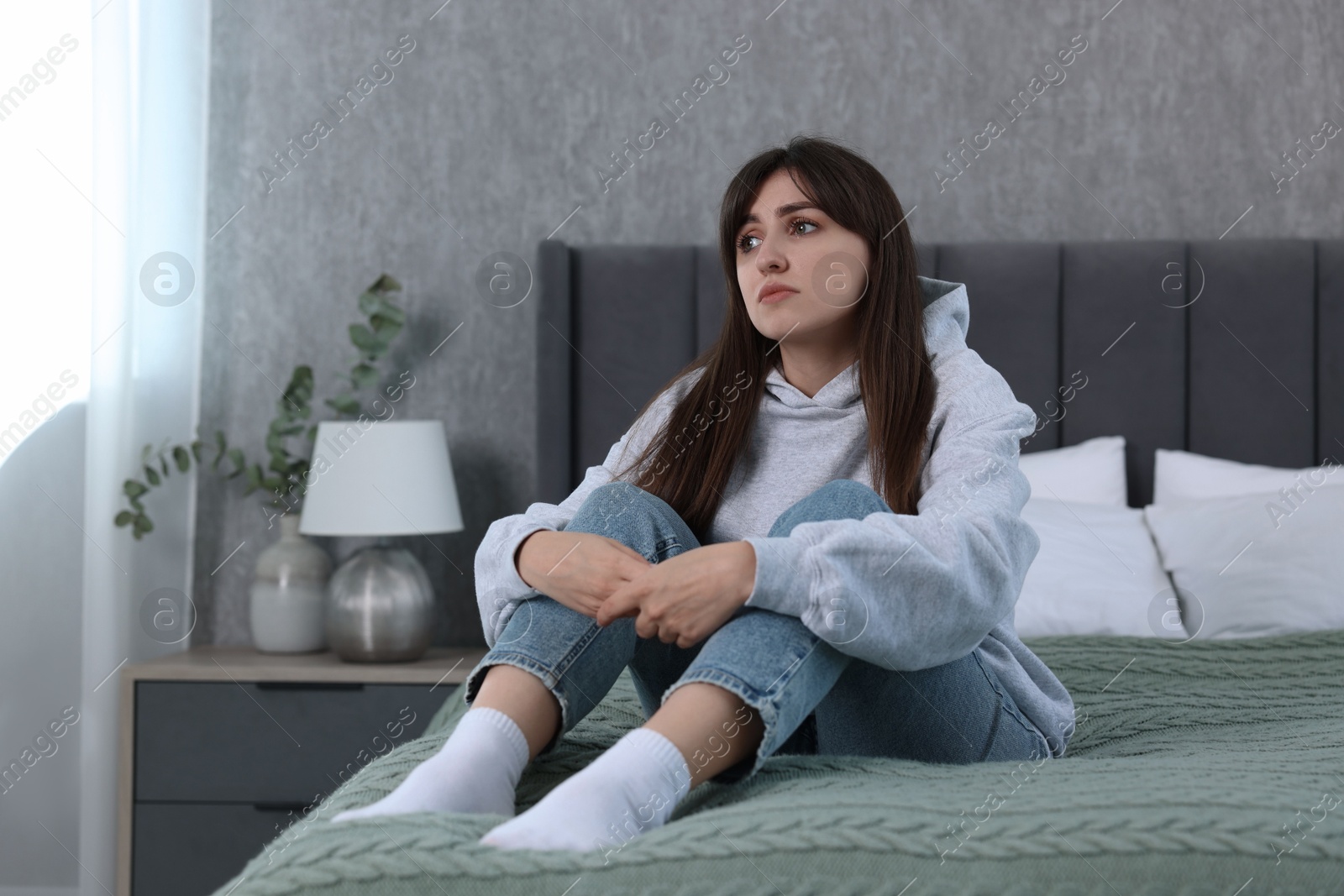 Photo of Loneliness concept. Sad woman sitting on bed at home