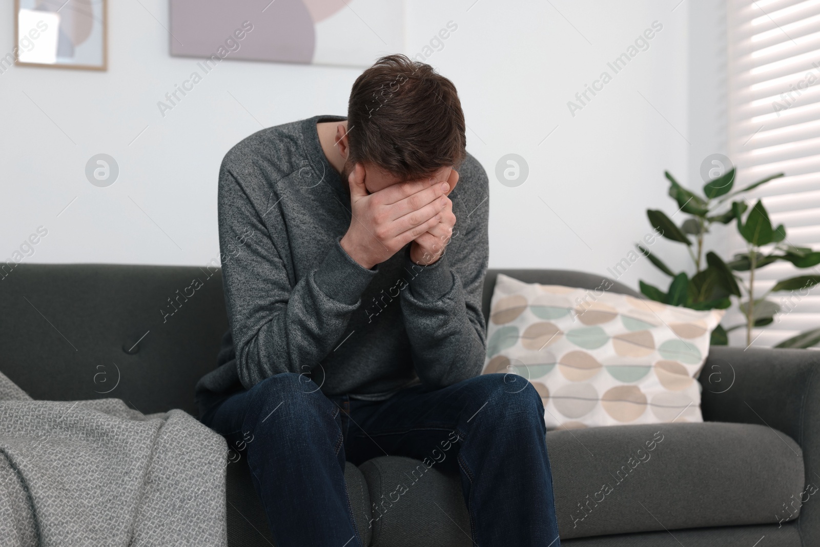 Photo of Loneliness concept. Sad man sitting on sofa at home