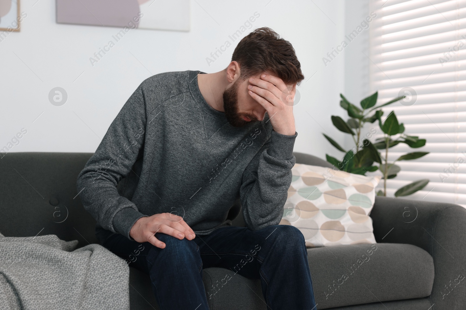 Photo of Loneliness concept. Sad man sitting on sofa at home